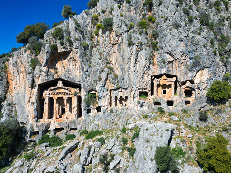 Aerial view of the ancient Lycian Rock Tombs of Kaunos carved into the steep limestone cliff face surrounded by rugged rocky terrain in Dalyan Mugla Turkiye. Aerial view of the ancient Lycian Rock Tombs of Kaunos carved into the steep limestone cliff face surrounded by rugged rocky terrain in Dalyan Mugla Turkiye.