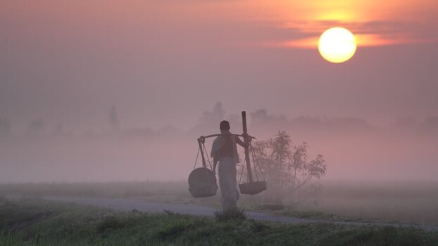 View of a man carrying baskets at sunrise in Bogura Bangladesh. View of a man carrying baskets at sunrise in Bogura Bangladesh.
