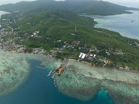 Aerial view of the vibrant turquoise waters meeting the lush green coastline at Karimunjawa ferry harbour Karimunjawa Jawa Tengah Indonesia. Aerial view of the vibrant turquoise waters meeting the lush green coastline at Karimunjawa ferry harbour Karimunjawa Jawa Tengah Indonesia.