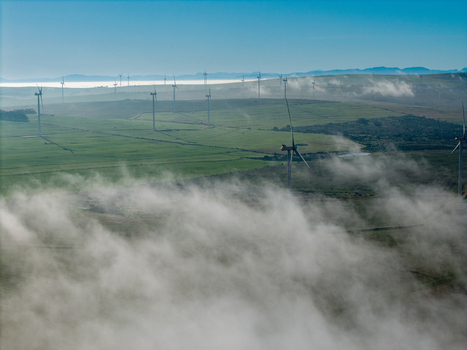 Aerial view of wind turbines standing in green fields amidst low lying morning mist in the rolling landscape of Vredenburg Western Cape South Africa. Aerial view of wind turbines standing in green fields amidst low lying morning mist in the rolling landscape of Vredenburg Western Cape South Africa.