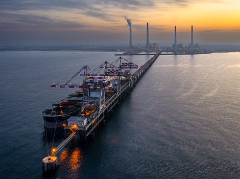 Aerial view of Orot Rabin Power Plant with its tall chimneys and a large coal carrier ship docked at the long pier during a golden sunset in Hadera Haifa District Israel. Aerial view of Orot Rabin Power Plant with its tall chimneys and a large coal carrier ship docked at the long pier during a golden sunset in Hadera Haifa District Israel.