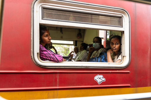 Sri Lanka 06 February 2026 View of passengers looking out of the window of a red train carriage with a yellow stripe.