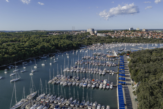 Aerial view of the marina in Pjescana Uvala with sailboats and yachts docked along piers surrounded by forest and buildings Pjescana Uvala Istarska zupanija Croatia.