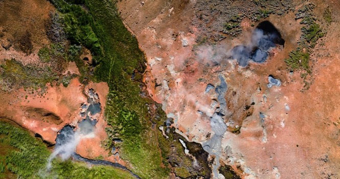 Aerial view of the geothermal landscape of Grensdalur showing steaming vents colorful mineral deposits and vibrant green vegetation in Sveitarfelagid Olfus Iceland. Aerial view of the geothermal landscape of Grensdalur showing steaming vents colorful mineral deposits and vibrant green vegetation in Sveitarfelagid Olfus Iceland.