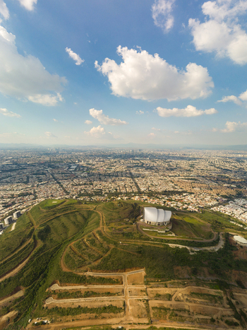 Aerial view of a modern building situated on a grassy hill overlooking the sprawling urban landscape of Tlaquepaque Jalisco Mexico. Aerial view of a modern building situated on a grassy hill overlooking the sprawling urban landscape of Tlaquepaque Jalisco Mexico.