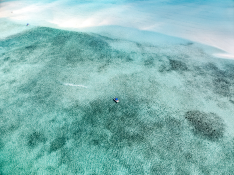 Aerial view of Man O War Cay Sandbar with a small boat anchored in crystal clear turquoise water in Rolletown Exuma The Bahamas. Aerial view of Man O War Cay Sandbar with a small boat anchored in crystal clear turquoise water in Rolletown Exuma The Bahamas.