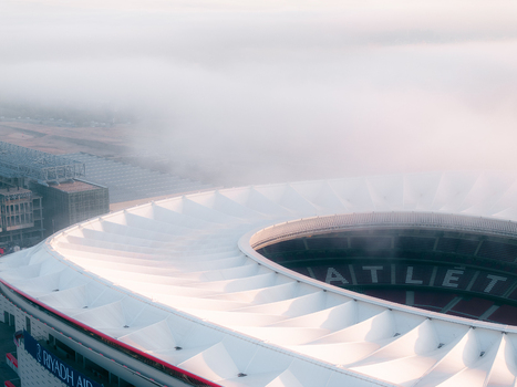 Aerial view of Riyadh Air Metropolitano Stadium partially obscured by morning mist showcasing the distinctive white roof structure and seating in Madrid Comunidad de Madrid Spain.