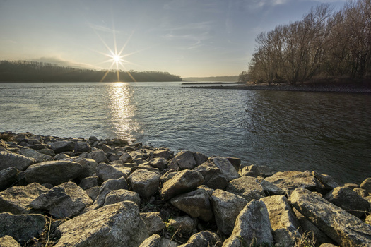 View of the Danube river near Devin at sunset with a rocky shoreline and bare winter trees in Bratislava IV Bratislava Region Slovakia. View of the Danube river near Devin at sunset with a rocky shoreline and bare winter trees in Bratislava IV Bratislava Region Slovakia.