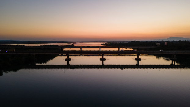 Aerial view of the Jhelum Bridge spanning across the calm river with a vibrant sunset sky and distant mountains Jhelum Punjab Pakistan. Aerial view of the Jhelum Bridge spanning across the calm river with a vibrant sunset sky and distant mountains Jhelum Punjab Pakistan.