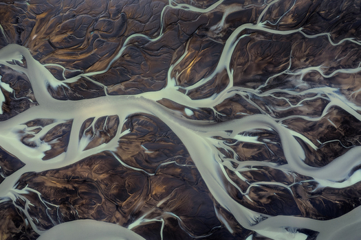 Aerial view of the braided river system in the Iceland Highlands with glacial sediment flowing through dark volcanic sand Iceland Iceland. Aerial view of the braided river system in the Iceland Highlands with glacial sediment flowing through dark volcanic sand Iceland Iceland.