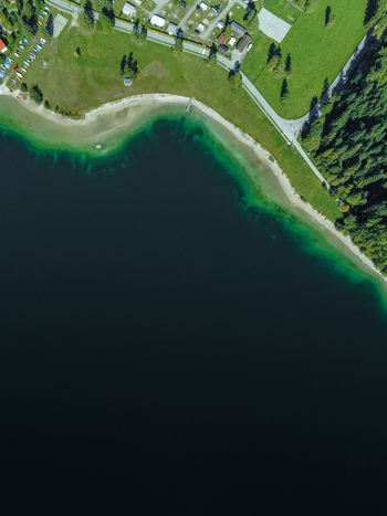 Aerial view of Plansee lake with its turquoise waters sandy shoreline surrounding green meadows and dense forest in Reutte District Tyrol Austria. Aerial view of Plansee lake with its turquoise waters sandy shoreline surrounding green meadows and dense forest in Reutte District Tyrol Austria.