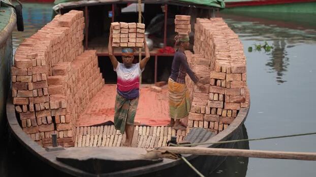 View of workers carrying bricks on a boat in Aminbazar Bangladesh. View of workers carrying bricks on a boat in Aminbazar Bangladesh.