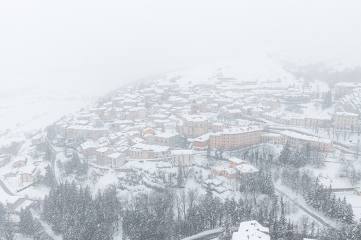 Aerial view of the snow covered town of Rivisondoli with historic stone buildings and surrounding pine forests in Rivisondoli Abruzzo Italy.