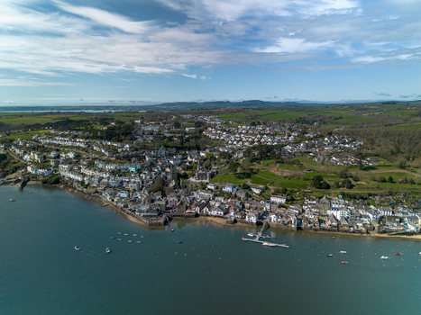 Aerial view of the historic town of Fowey with boats moored along the riverbank surrounded by green hills and coastal landscape in Fowey Cornwall United Kingdom. Aerial view of the historic town of Fowey with boats moored along the riverbank surrounded by green hills and coastal landscape in Fowey Cornwall United Kingdom.
