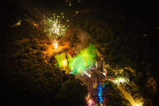 Aerial view of a night event in a quarry with vibrant fireworks and a large crowd gathered under green stage lighting in Vintijan Istria County Croatia. Aerial view of a night event in a quarry with vibrant fireworks and a large crowd gathered under green stage lighting in Vintijan Istria County Croatia.