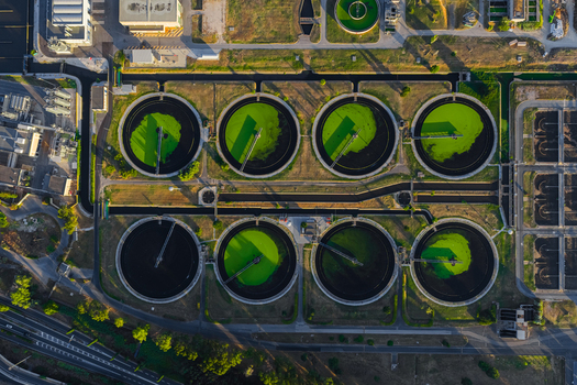 Aerial view of the water treatment plant featuring circular sedimentation tanks with green water industrial infrastructure and surrounding roads in Rome Lazio Italy.