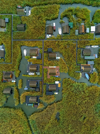 Aerial view of stilt houses nestled within dense reed beds on the water featuring wooden walkways and small boats moored at the docks in Rust Burgenland Austria.