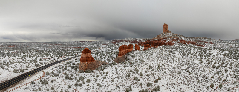 Aerial view of red rock buttes and a winding road in a snow covered desert landscape under dark stormy clouds Page Arizona United States.