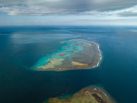 Aerial view of a submerged reef reveals a kaleidoscope of turquoise and tan hues against the deep blue sea Goro South Province New Caledonia. Aerial view of a submerged reef reveals a kaleidoscope of turquoise and tan hues against the deep blue sea Goro South Province New Caledonia.