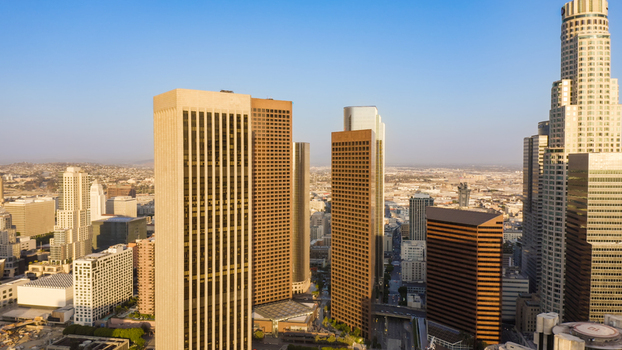 Aerial view of the Los Angeles skyline featuring modern skyscrapers and office buildings under a clear blue sky in Los Angeles California United States.