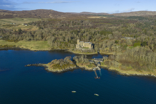 Aerial view of Dunvegan Castle and Gardens on the shores of Loch Dunvegan surrounded by lush woodlands and rolling hills Isle of Skye Scotland United Kingdom. Aerial view of Dunvegan Castle and Gardens on the shores of Loch Dunvegan surrounded by lush woodlands and rolling hills Isle of Skye Scotland United Kingdom.