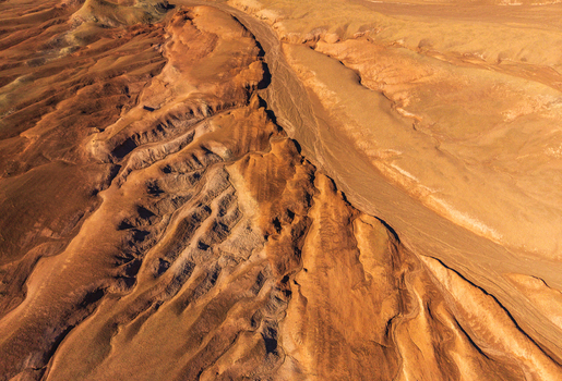 Aerial view of the rugged arid landscape of the Atacama Desert with deep ravines undulating sand dunes and textured rock formations in San Pedro de Atacama Antofagasta Chile. Aerial view of the rugged arid landscape of the Atacama Desert with deep ravines undulating sand dunes and textured rock formations in San Pedro de Atacama Antofagasta Chile.