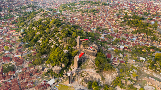 Aerial view of a hill covered in lush greenery crowned with structures and stairways amidst a sprawling cityscape Ibadan Nigeria. Aerial view of a hill covered in lush greenery crowned with structures and stairways amidst a sprawling cityscape Ibadan Nigeria.
