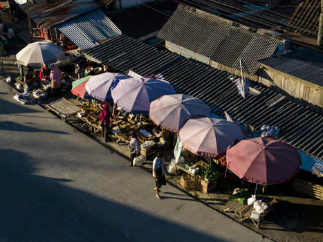 Aerial view of traditional market stalls with colorful umbrellas and people walking along the street in Kemalang Central Java Indonesia.