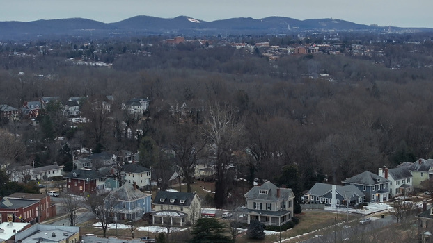 Aerial view of residential houses nestled among bare winter trees with rolling hills in the background in Lynchburg Virginia United States.