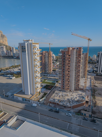 Aerial view of modern high rise residential buildings under construction with tower cranes coastal urban development and Mediterranean sea in Calp Valencian Community Spain. Aerial view of modern high rise residential buildings under construction with tower cranes coastal urban development and Mediterranean sea in Calp Valencian Community Spain.