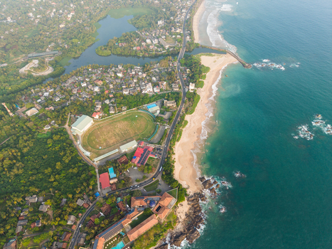 Aerial view of the coastal landscape featuring a sandy beach turquoise ocean a stadium and lush tropical greenery in Galle Southern Province Sri Lanka.