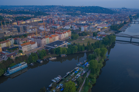Aerial view of the Vltava river flowing through the historic city of Prague with residential buildings bridges and boats moored along the banks in Prague Prague Czechia.