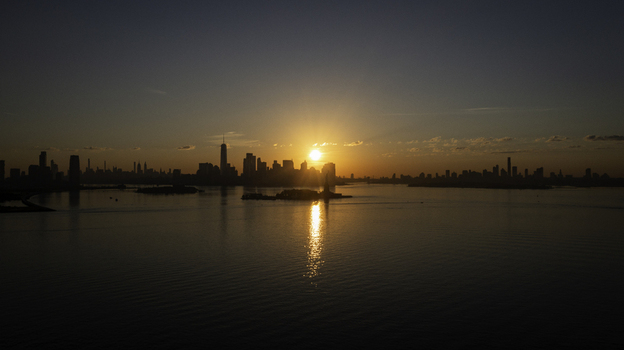 Aerial view of the New York skyline at sunset with the sun reflecting on the calm waters of the harbor in New York New York United States.