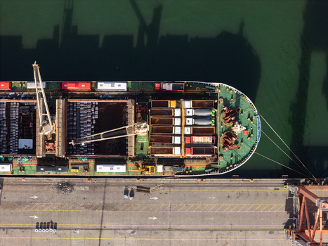 Aerial view of a large cargo ship docked at the industrial port with cranes and containers in Bajos de Haina San Cristobal Provinc Dominican Republic.
