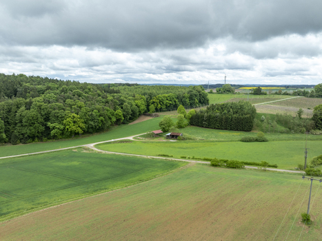 Aerial view of lush green fields and dense forest under a cloudy sky with a small rural shed Aiglsbach Bavaria Germany. Aerial view of lush green fields and dense forest under a cloudy sky with a small rural shed Aiglsbach Bavaria Germany.