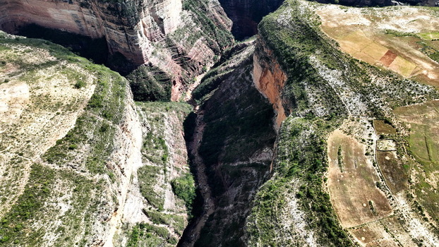 Aerial view of El Vergel canyon featuring steep rock walls and a narrow riverbed surrounded by arid landscape and agricultural fields in Torotoro Potosi Department Bolivia. Aerial view of El Vergel canyon featuring steep rock walls and a narrow riverbed surrounded by arid landscape and agricultural fields in Torotoro Potosi Department Bolivia.
