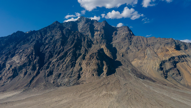 Aerial view of the rugged Shigar River valley surrounded by towering mountain peaks and rocky slopes under a clear blue sky in Skardu Gilgit Pakistan.