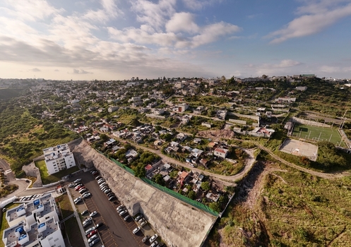 Santiago de Queretaro Queretaro Mexico 25 September 2026 Aerial view of Anillo Vial Fray Junipero Serra winding through the urban landscape with houses green hills and a parking lot.