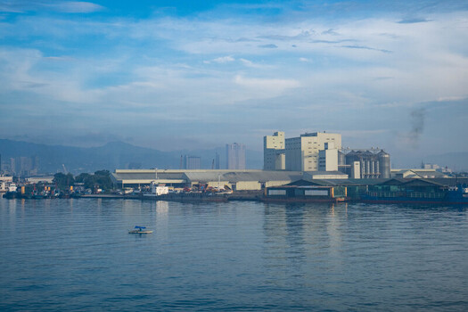 View of Cebu Port Authority industrial facilities with warehouses silos and ships docked along the waterfront under a blue sky in Cebu City Central Visayas Philippines. View of Cebu Port Authority industrial facilities with warehouses silos and ships docked along the waterfront under a blue sky in Cebu City Central Visayas Philippines.
