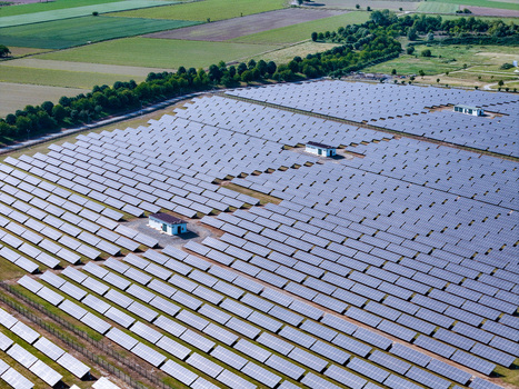 Aerial view of a large solar farm with rows of photovoltaic panels and small utility buildings surrounded by green fields Torrazza Piemonte Piemonte Italy. Aerial view of a large solar farm with rows of photovoltaic panels and small utility buildings surrounded by green fields Torrazza Piemonte Piemonte Italy.
