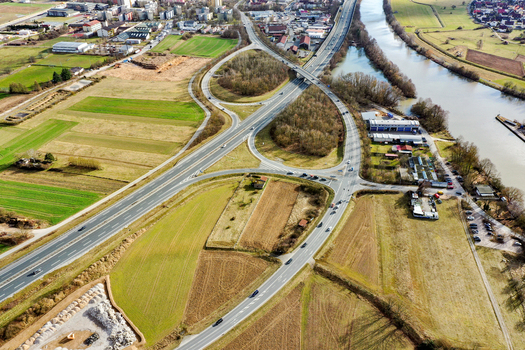 Aerial view of the highway interchange and bridge over the river surrounded by green fields and industrial buildings in Buttenheim Bavaria Germany. Aerial view of the highway interchange and bridge over the river surrounded by green fields and industrial buildings in Buttenheim Bavaria Germany.