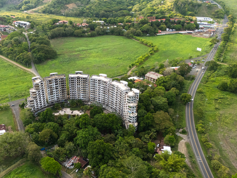 Aerial view of the abandoned Sonesta One Resort towers surrounded by dense tropical forest and rolling green hills under soft daylight in Jaco Provincia de Puntarenas Costa Rica. Aerial view of the abandoned Sonesta One Resort towers surrounded by dense tropical forest and rolling green hills under soft daylight in Jaco Provincia de Puntarenas Costa Rica.