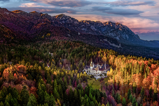 Sinaia Romania 21 September 2026 Aerial view of Peles Castle nestled in the dense colorful autumn forests of the Carpathian Mountains under a dramatic sunset sky. Sinaia Romania 21 September 2026 Aerial view of Peles Castle nestled in the dense colorful autumn forests of the Carpathian Mountains under a dramatic sunset sky.