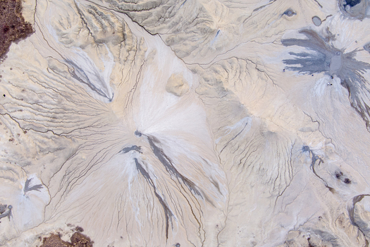 Aerial view of the Mud Volcanoes of Paclele Mari showing unique grey and beige mud formations with intricate drainage patterns in Paclele Buzau County Romania.