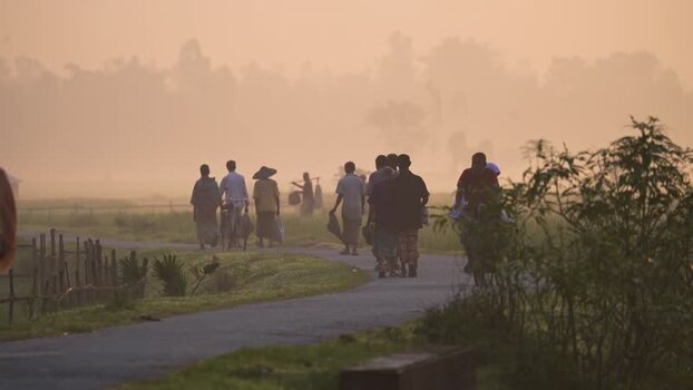 View of people walking on a rural road at dawn Bangladesh.