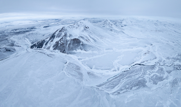 Aerial view of snow covered mountains and a winding river in the vast winter landscape of Egilsstadir Mulathing Iceland. Aerial view of snow covered mountains and a winding river in the vast winter landscape of Egilsstadir Mulathing Iceland.