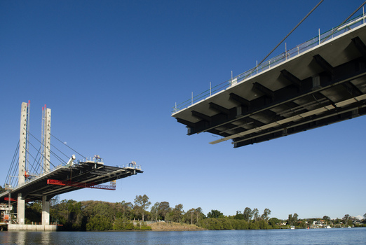 View of the construction of the Eleanor Schonell Bridge over the Brisbane River with concrete pillars steel cables and clear blue sky in Brisbane Queensland Australia.