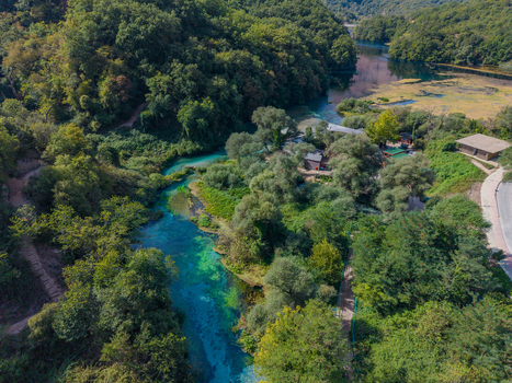 Aerial view of The Blue Eye a natural spring with vibrant turquoise water surrounded by lush green forest and trees in Saranda Qarku i Vlores Albania. Aerial view of The Blue Eye a natural spring with vibrant turquoise water surrounded by lush green forest and trees in Saranda Qarku i Vlores Albania.