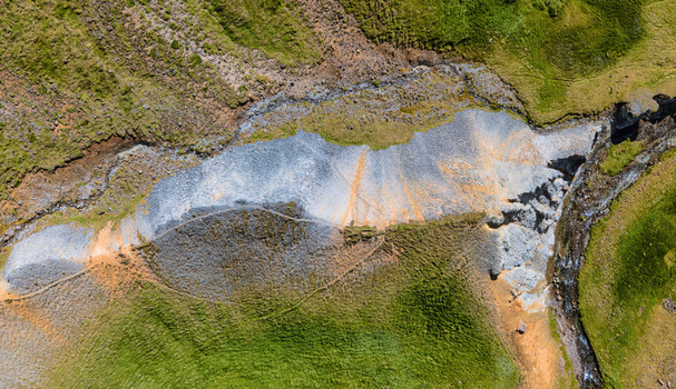 Aerial view of Grensdalur geothermal area featuring vibrant mineral deposits rocky terrain and lush green mossy slopes in Sveitarfelagid Olfus Iceland. Aerial view of Grensdalur geothermal area featuring vibrant mineral deposits rocky terrain and lush green mossy slopes in Sveitarfelagid Olfus Iceland.