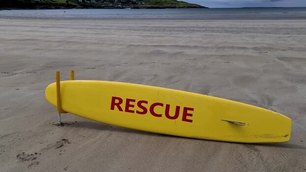 View of a yellow rescue surfboard on the beach in Ireland.